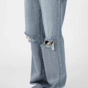 Blue-washed knee destroyed jeans